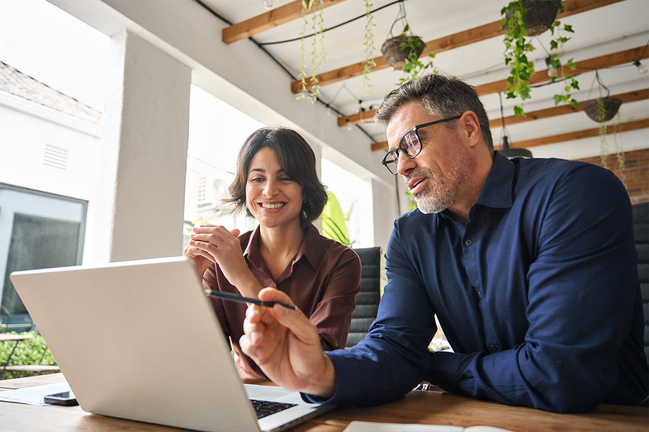 Real estate agent with client looking on laptop in modern office with city view